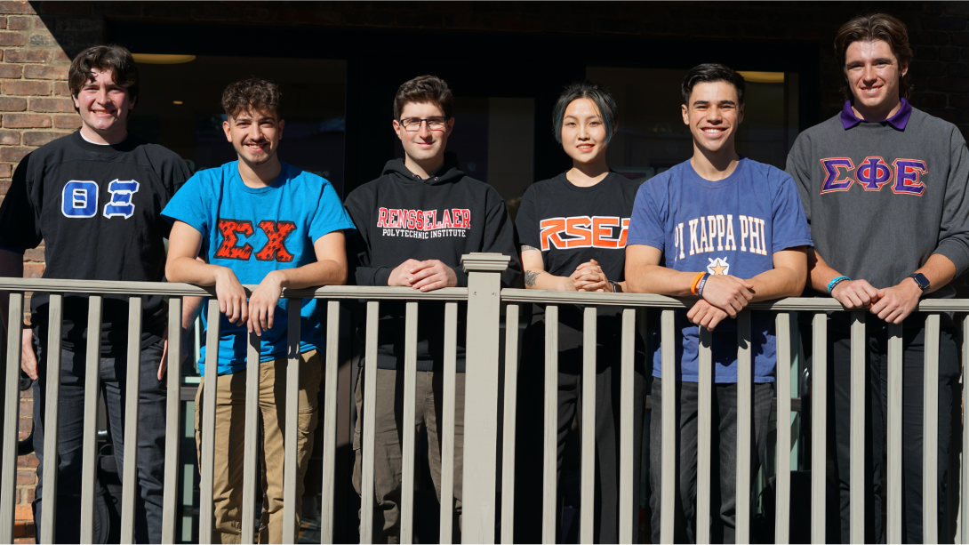 Students outside leaning against a railing